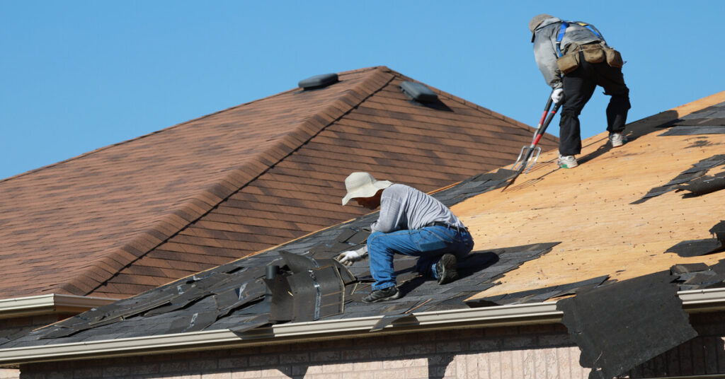 Roofers on the roof replacing roofing shingles